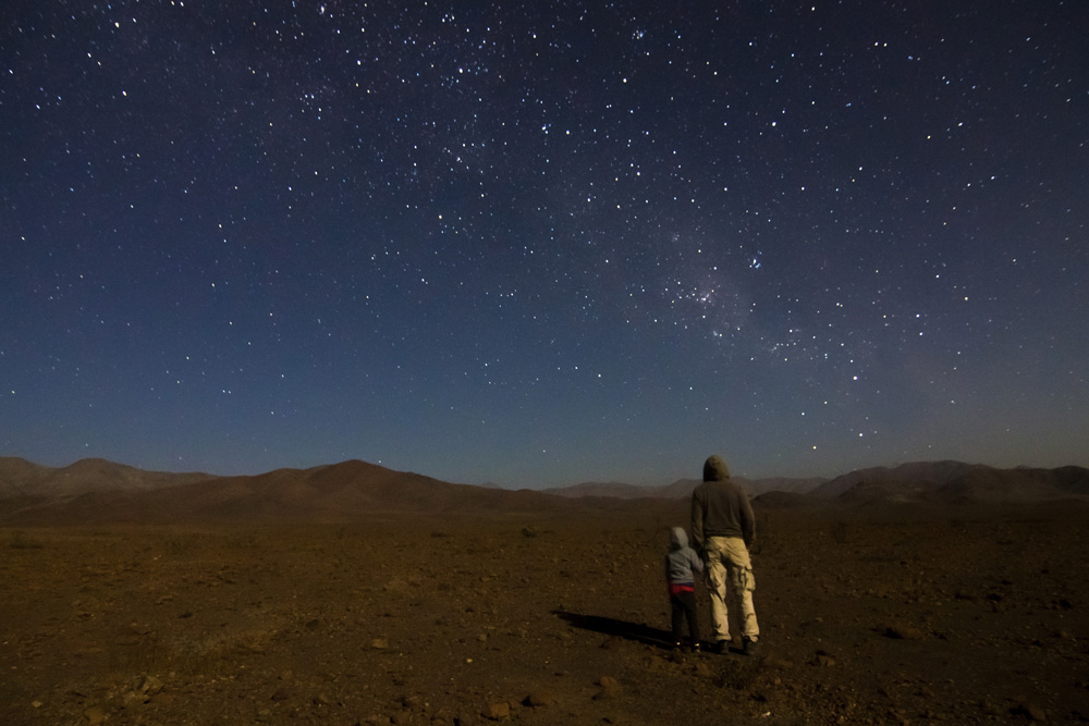 Mención honrosa 5: "Mostrando el hogar".  Autor: Rodrigo Escuti.  "Junto a mi nieto, gran compañero y aprendiz en las noches de observación. Esa noche buscábamos observar el cometa Lovejoy. Se aprecia la Vía Láctea, el Saco de Carbón y la Cruz del Sur". Foto tomada en diciembre 2014; región de Atacama.