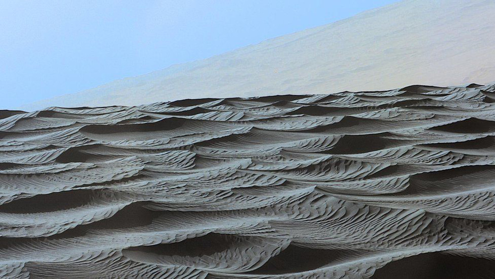 Este es el tope de una duna de arena en Marte, con otras donas borrosas al fondo y el cielo azul. Fue tomada con la sonda Curiosity el 13 de diciembre de 2015.